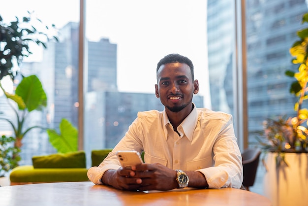 Photo un jeune homme assis sur une table à la maison.