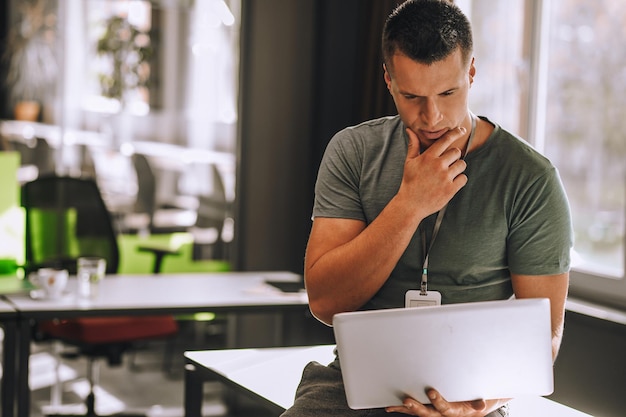 Jeune homme assis sur la table avec un ordinateur portable