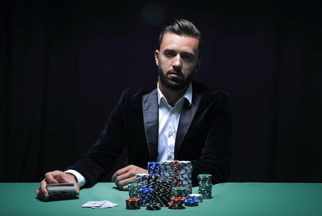 Jeune homme assis à la table de poker avec ses jetons et ses cartes devant lui