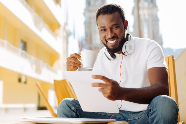 Jeune homme assis sur une terrasse et lisant un article