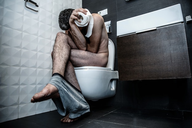 Jeune homme assis sur les toilettes dans la salle de repos