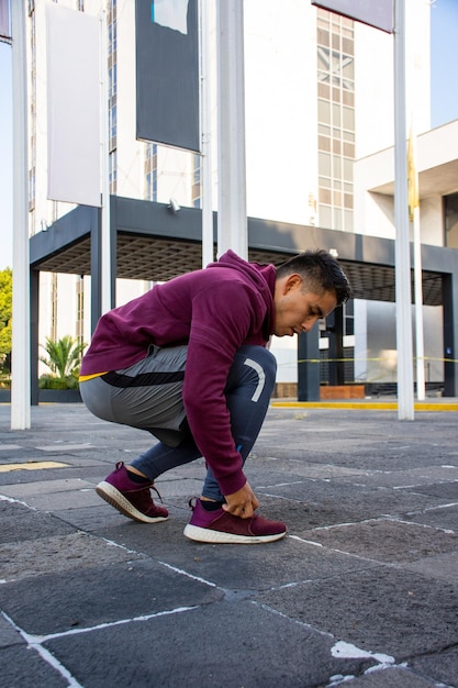 Jeune homme athlétique attachant ses lacets dans la rue