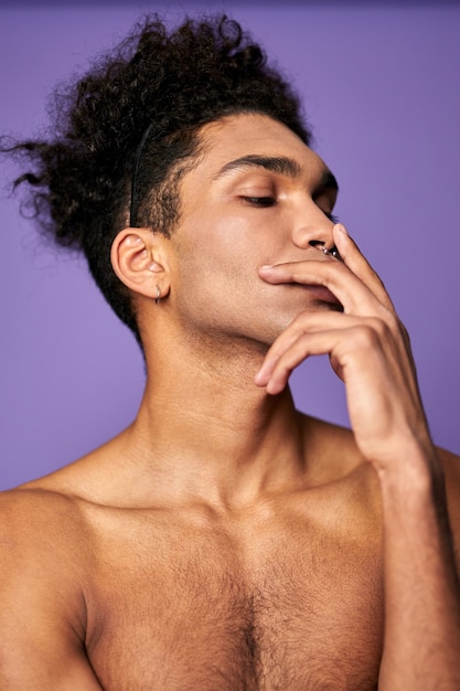 Jeune homme athlétique avec les doigts sur le visage portrait style de mode transgenre tourné modèle de genre trans