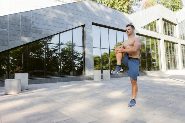 Jeune homme athlétique faisant l'échauffement avant l'entraînement en plein air. Mode de vie sain. Concept de remise en forme