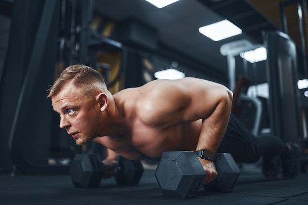 Jeune homme athlétique faisant des pompes dans la salle de gym mec musclé et fort exercice