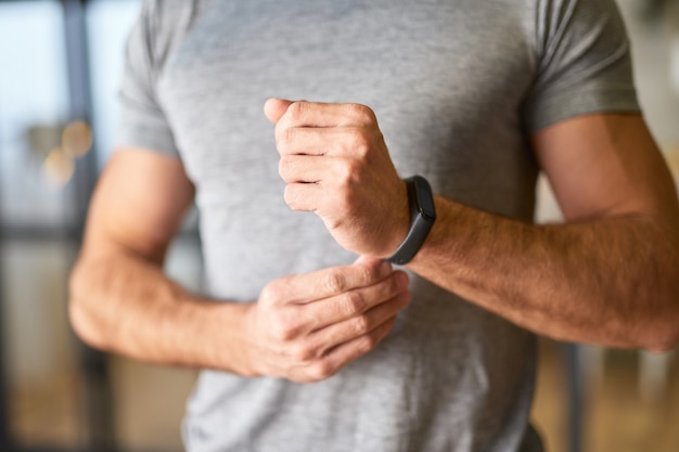 Jeune homme athlétique mettant une montre intelligente sur son poignet