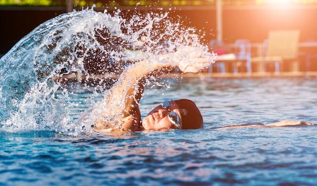 Jeune homme athlétique nageant dans la piscine