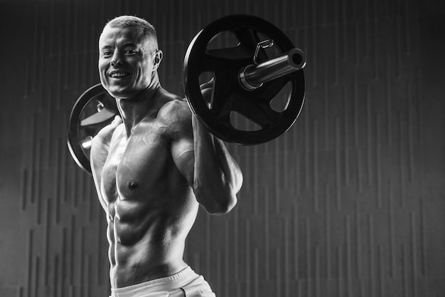 Jeune homme athlétique pompage des muscles dans la salle de gym à l'entraînement Sport et concept de soins de santé backgroun