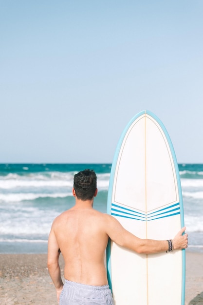 Jeune homme athlétique surfant sur la plage