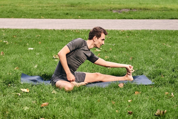 Jeune homme athlétique en tenue de sport, faire du yoga dans le parc