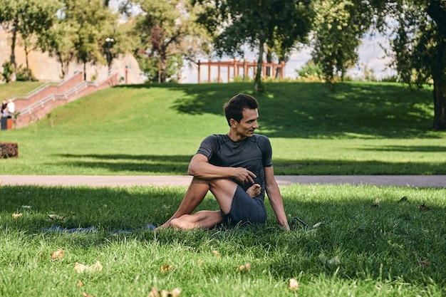 Jeune homme athlétique en tenue de sport, faire du yoga dans le parc