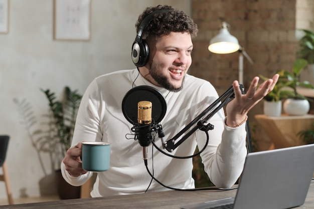 Jeune homme au casque utilisant un microphone et enregistrant un podcast ou une interview pour la radio