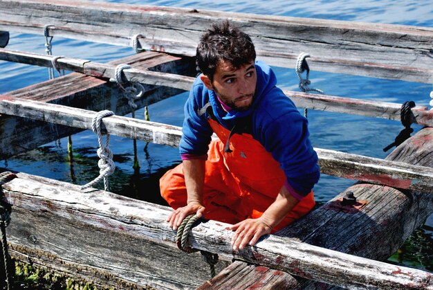 Photo un jeune homme au milieu de planches de bois dans la rivière