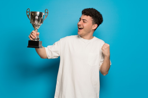 Jeune homme au mur bleu tenant un trophée