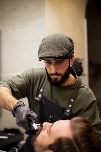 Photo jeune homme au salon de coiffure se faisant tailler la barbe