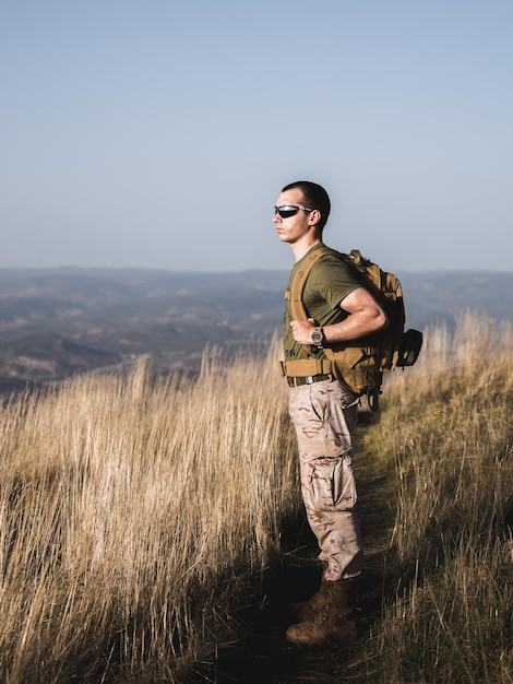 Jeune homme au sommet d'une montagne avec des lunettes de soleil et un sac à dos