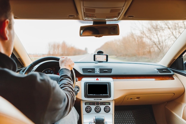 Le jeune homme au volant de la voiture moderne sur route goudronnée