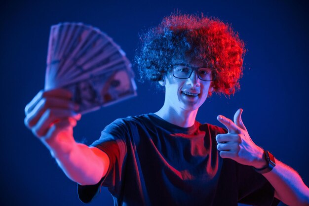 Photo un jeune homme aux cheveux bouclés est éclairé à l'intérieur par un éclairage au néon