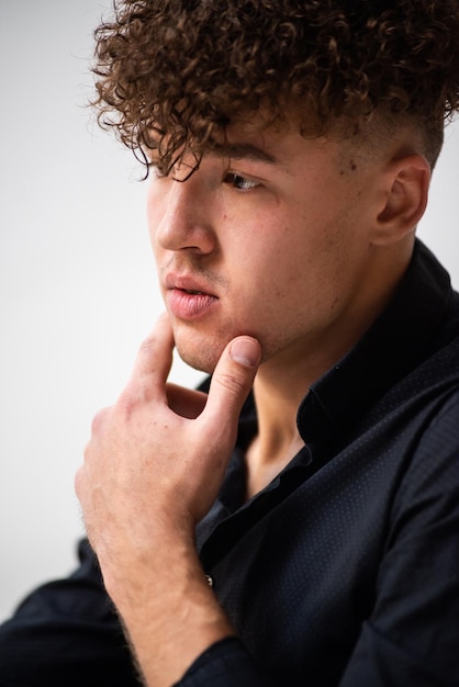 Un jeune homme aux cheveux bouclés regarde la caméra.