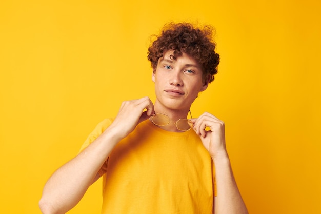 Jeune homme aux cheveux bouclés tshirt jaune lunettes mode gestes de la main fond jaune inchangé