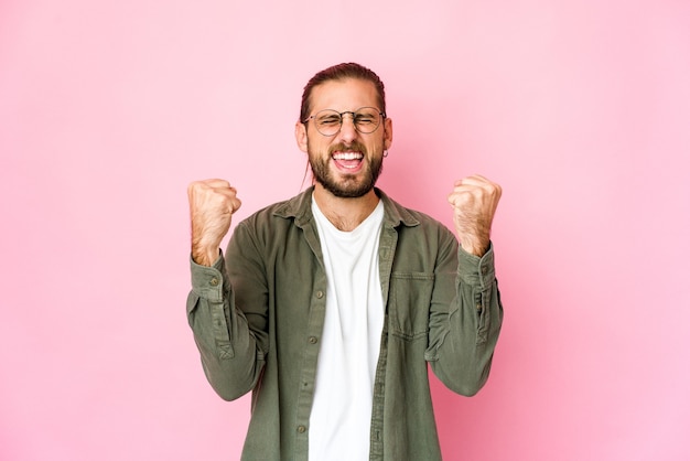 Jeune homme aux cheveux longs a l'air insouciant et excité. Concept de victoire.