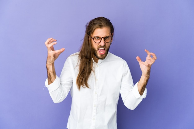 Un jeune homme aux cheveux longs crie de rage.