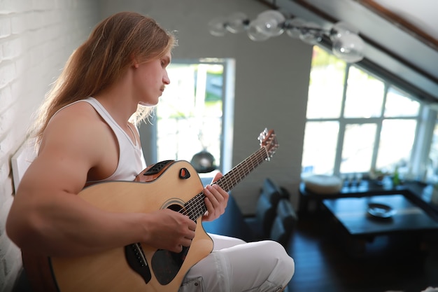 Jeune homme aux cheveux longs avec une guitare acoustique