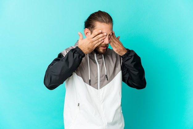 Jeune homme aux cheveux longs a peur de couvrir les yeux avec les mains.