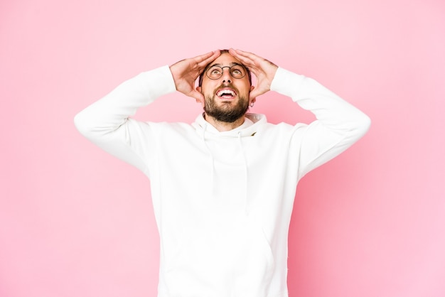 Jeune homme aux cheveux longs regarde rire joyeusement en gardant les mains sur la tête