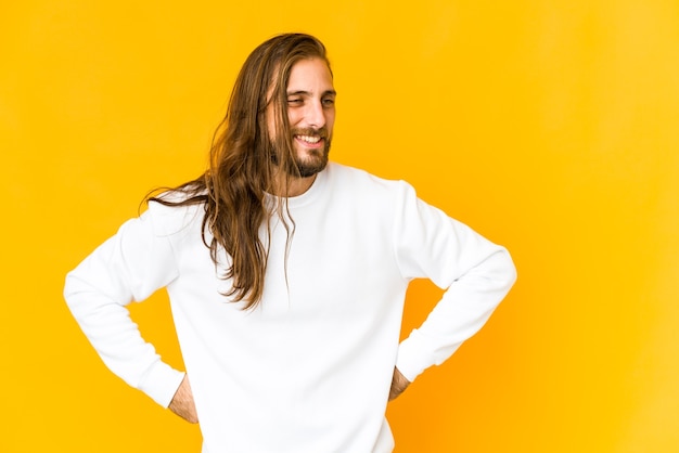 Le jeune homme aux cheveux longs rit joyeusement et s'amuse à garder les mains sur le ventre.