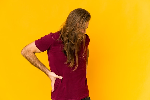 Jeune homme aux cheveux longs souffre de maux de dos.