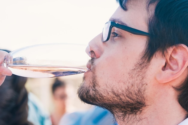 Jeune homme aux cheveux noirs avec une barbe et des verres buvant du champagne dans un verre Célébration de mariage Apéritif