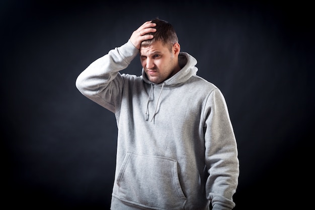 Un jeune homme aux cheveux noirs vêtu d’un sweat-shirt gris sportif était contrarié