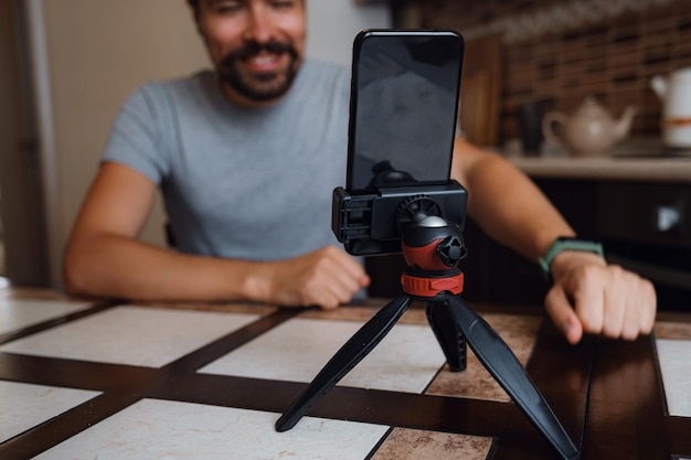 Jeune homme ayant un appel vidéo via smartphone dans le bureau à domicile