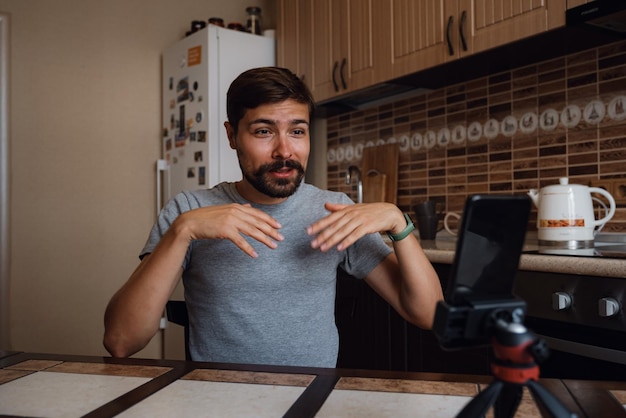 Jeune homme ayant un appel vidéo via smartphone dans le bureau à domicile