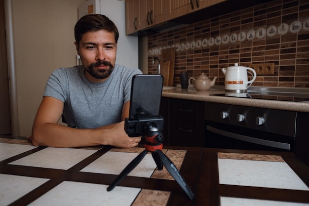 Photo jeune homme ayant un appel vidéo via smartphone dans le bureau à domicile