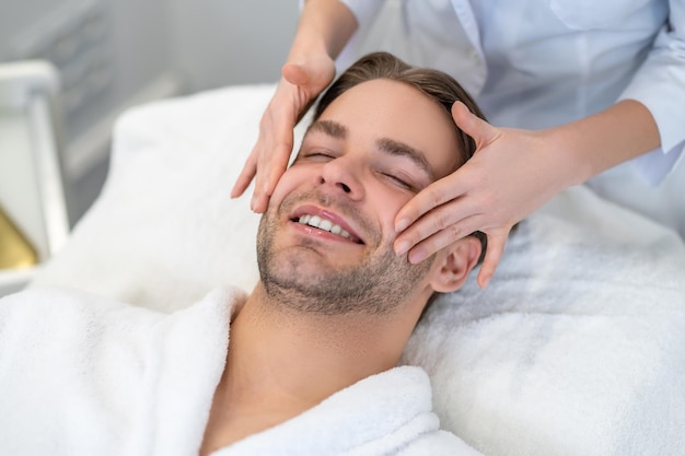 Jeune homme ayant un massage du visage dans un salon de beauté