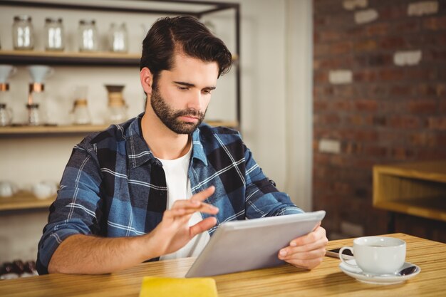 Jeune homme ayant une tasse de café avec tablette