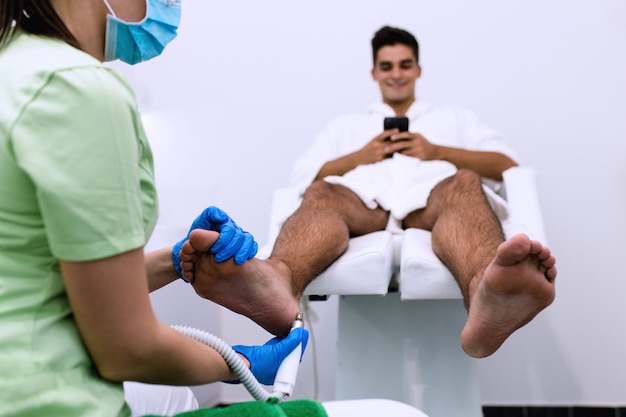 Jeune homme ayant un traitement de pédicure dans un salon de beauté moderne.