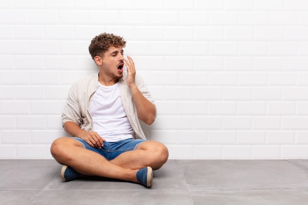 Jeune homme bâillant paresseusement tôt le matin, se réveillant et à la somnolence