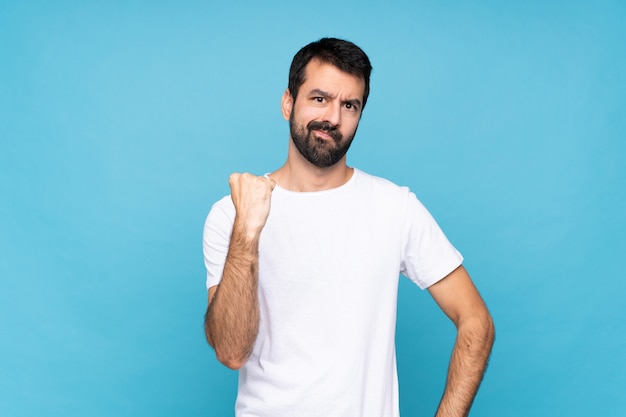 Jeune homme à la barbe sur bleu isolé avec un geste de colère