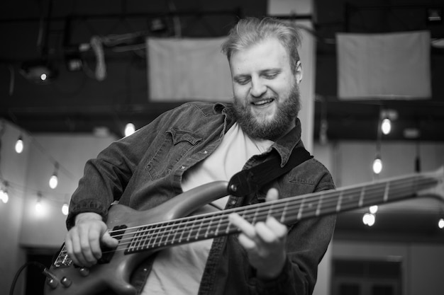 Un jeune homme avec une barbe joue de la guitare basse à cinq cordes