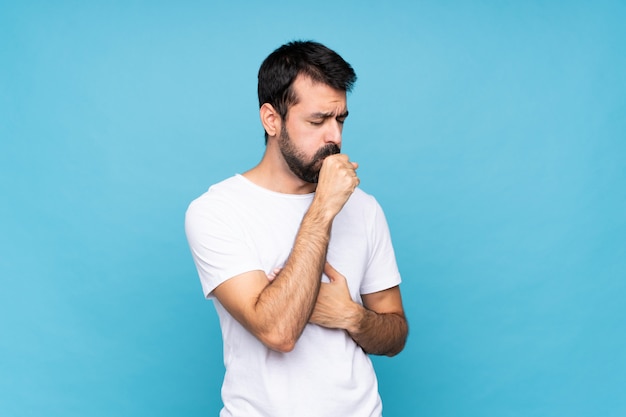 Jeune homme à la barbe sur un mur bleu isolé souffre de toux et se sent mal