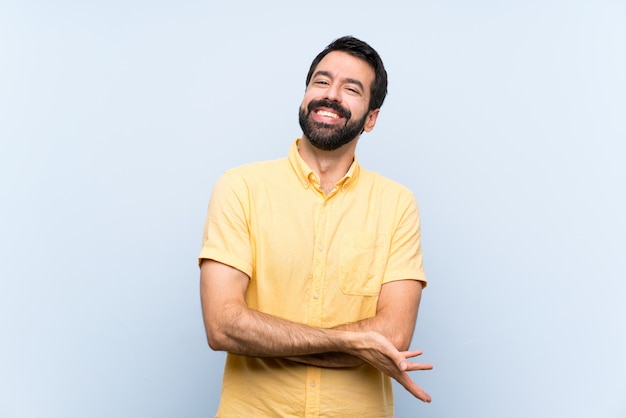 Jeune homme à la barbe sur mur bleu isolé souriant