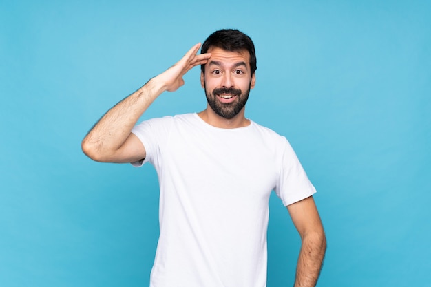 Jeune homme à la barbe sur un mur bleu isolé vient de réaliser quelque chose et a l'intention de la solution