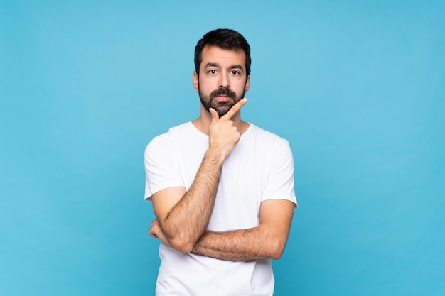 Jeune homme à la barbe sur la pensée de fond bleu isolé