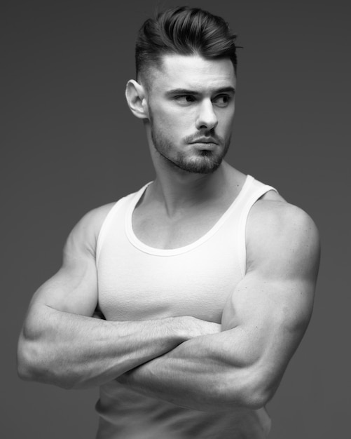 Jeune homme avec une barbe en t-shirt. Portrait masculin sur fond gris. Homme élégant. photo noir et blanc. Homme de sport. modèle de fitness. portrait en studio. Portrait masculin élégant sur fond gris.