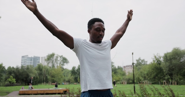 Photo jeune homme barbu africain qui s'étend du corps avant la course du matin au parc verdoyant. un homme musulman en bonne santé s'étire avant de courir au parc.