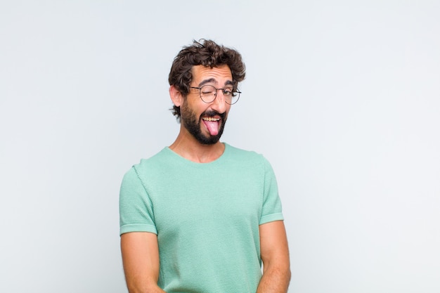 Jeune homme barbu avec une attitude joyeuse, insouciante et rebelle, plaisantant et sortant la langue, s'amusant