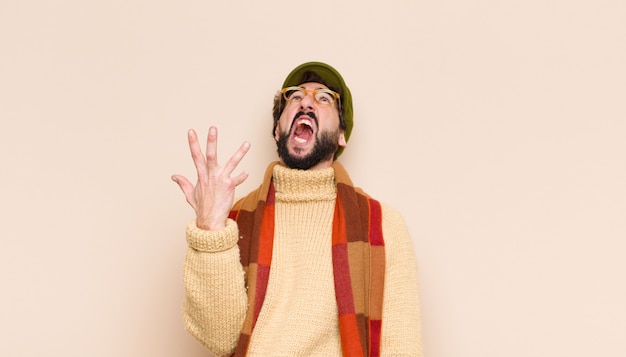 Jeune homme barbu cool regardant en colère, ennuyé et frustré hurlant wtf ou ce qui ne va pas avec vous